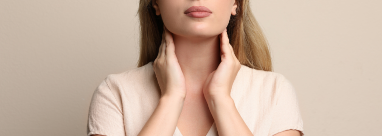 Mujer tocándose el cuello a la altura de la tiroides, representando síntomas relacionados con el hipotiroidismo, en el contexto de una nota sobre su impacto en la fertilidad.