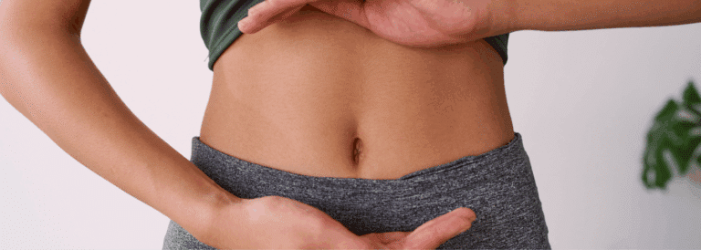 Mujer señalando su abdomen bajo, representación visual de salud uterina y microbiota vaginal.