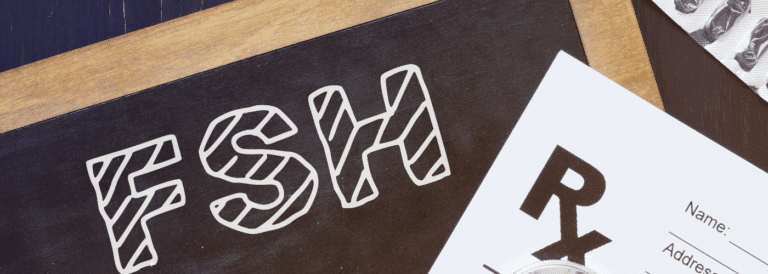 Placa negra con las siglas FSH en tipografía blanca, acompañada de una receta médica y un blíster de comprimidos sobre una superficie de madera.